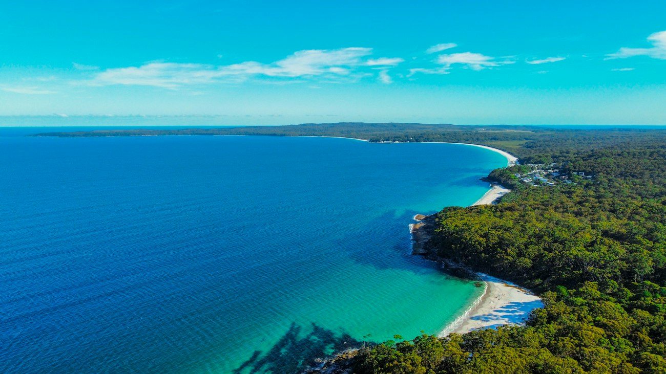 A broad blue bay with a green Jervis Bay coastline