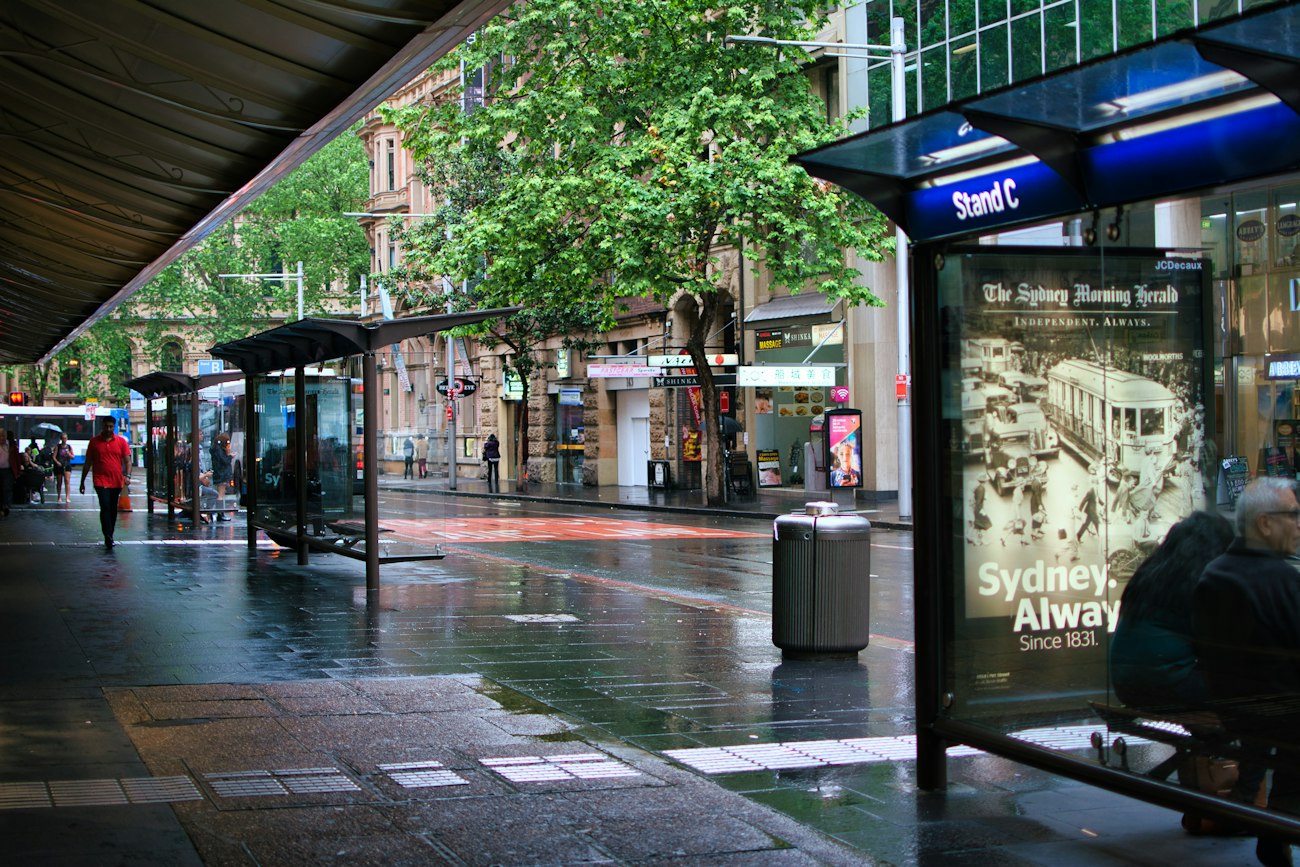Rain on a Sydney pavement beside a covered bus stop