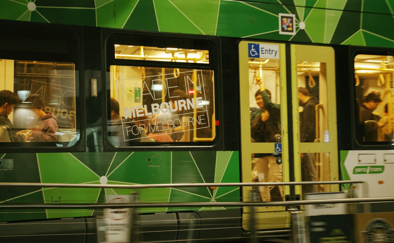 A green Melbourne tram at a city stop