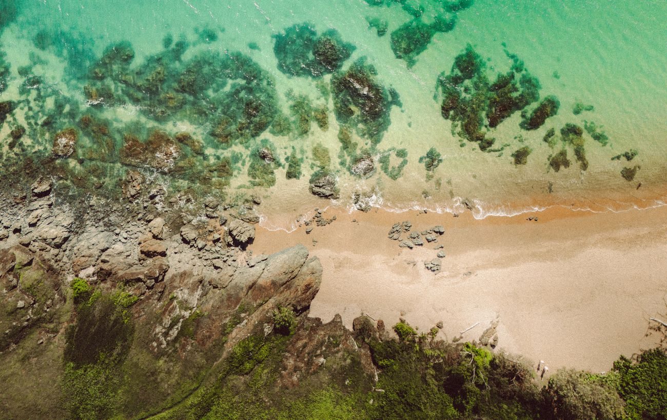 Clear water and rock formations beside a Yeppoon beach from above