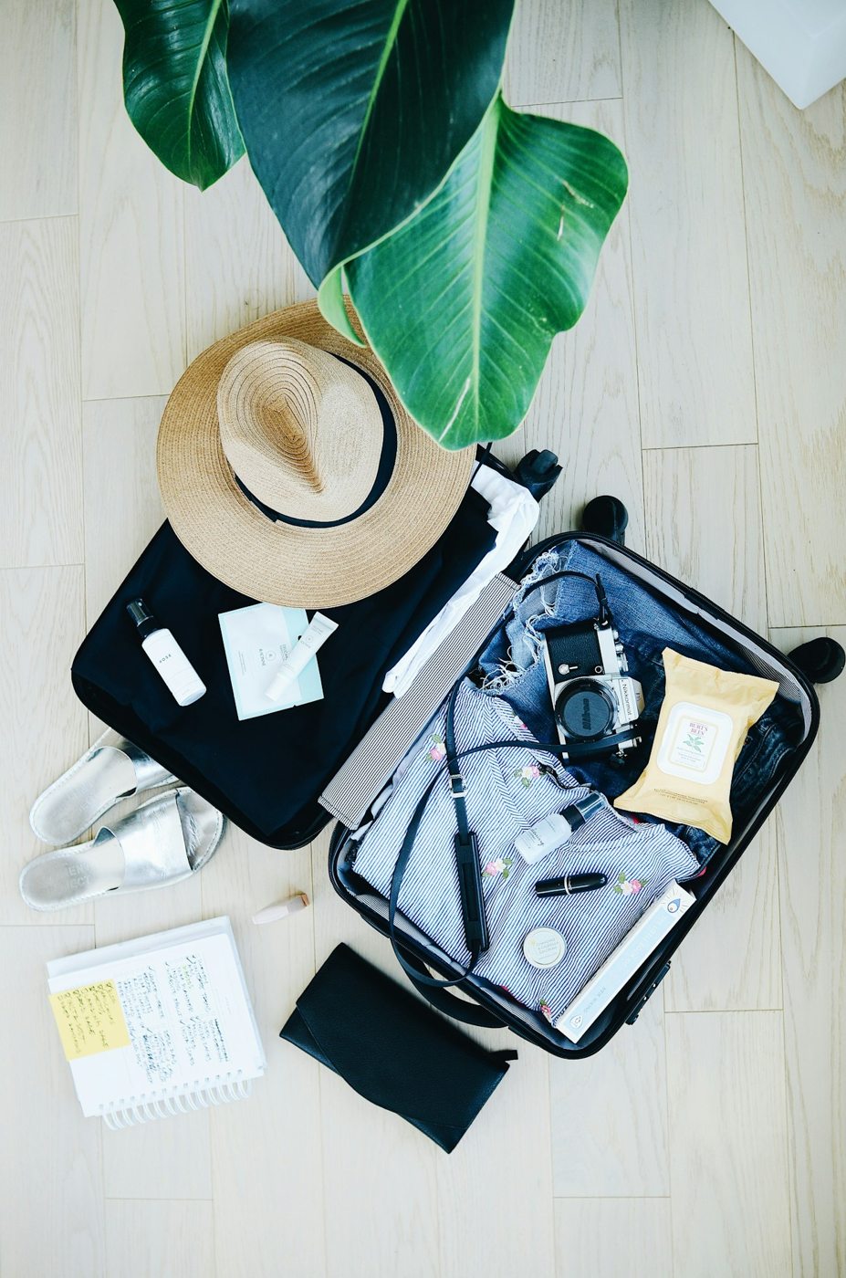 An open suitcase with clothing and a sun hat