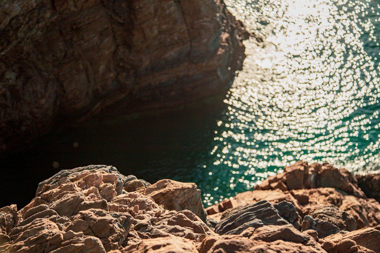 Sunlit water below a rocky cliff at Second Valley