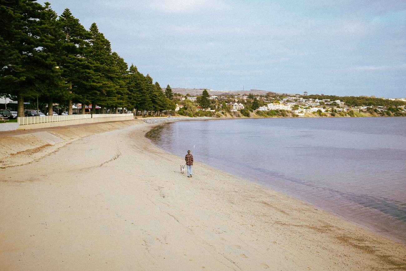 A visitor walking along the Port Lincoln waterfront beach