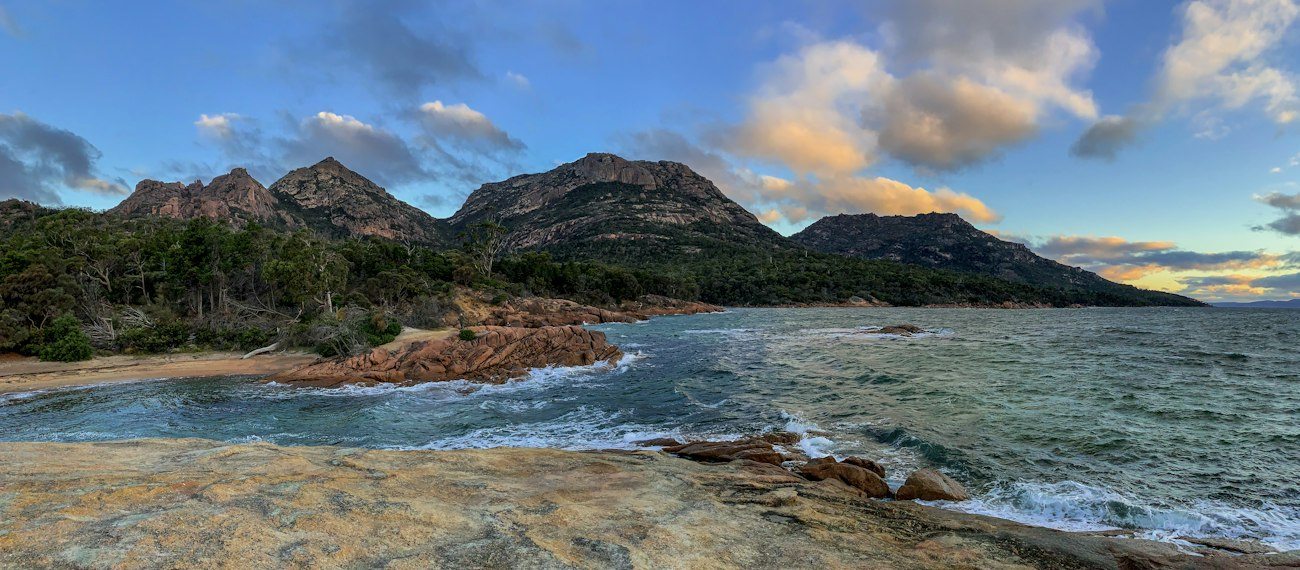 Rocky shoreline beneath the Freycinet mountains