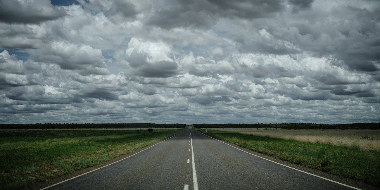 A long Northern Territory highway beneath heavy clouds