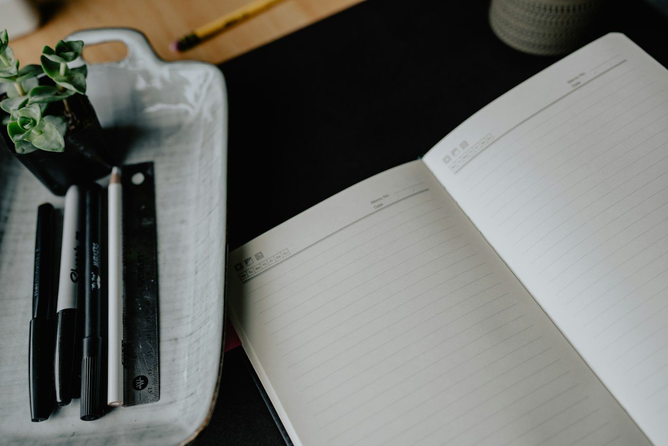 An open notebook with blank planning pages and pens